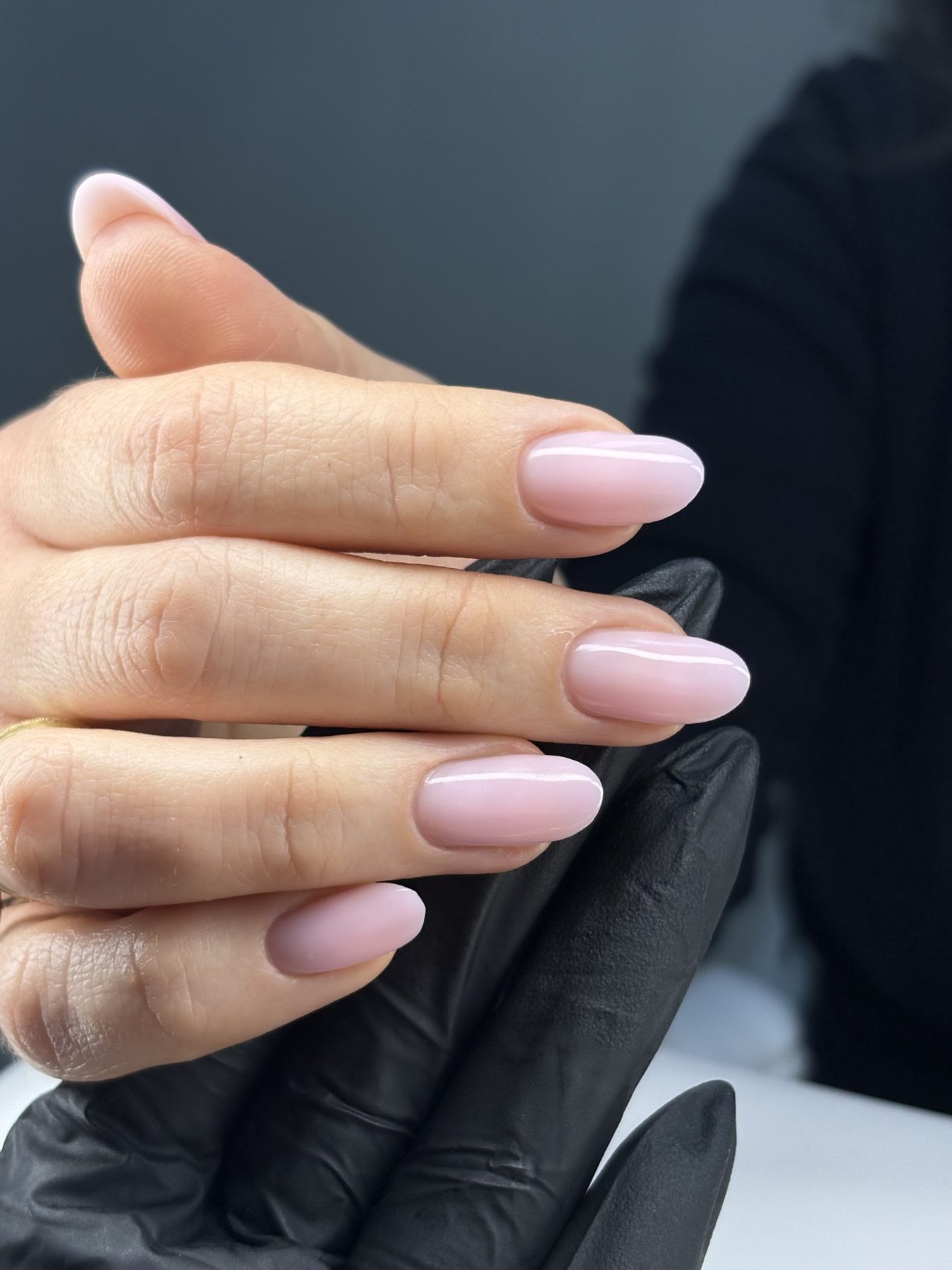 Melkroze amandelnagels, vastgehouden door Elma's zwarte handschoen